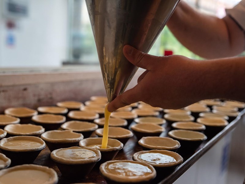 A person is filling small pie crust with filling.