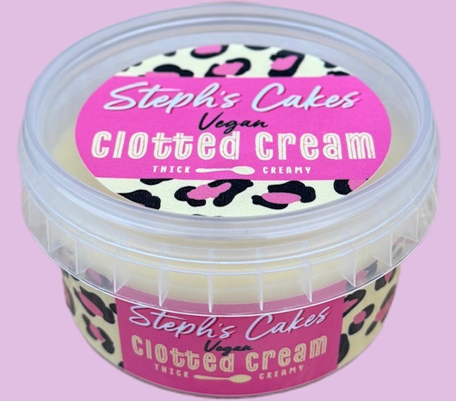 A clear plastic tub labeled “Steph’s Cakes Vegan Clotted Cream” with a pink and leopard-print design. The text highlights “Thick & Creamy” as a feature of the product.