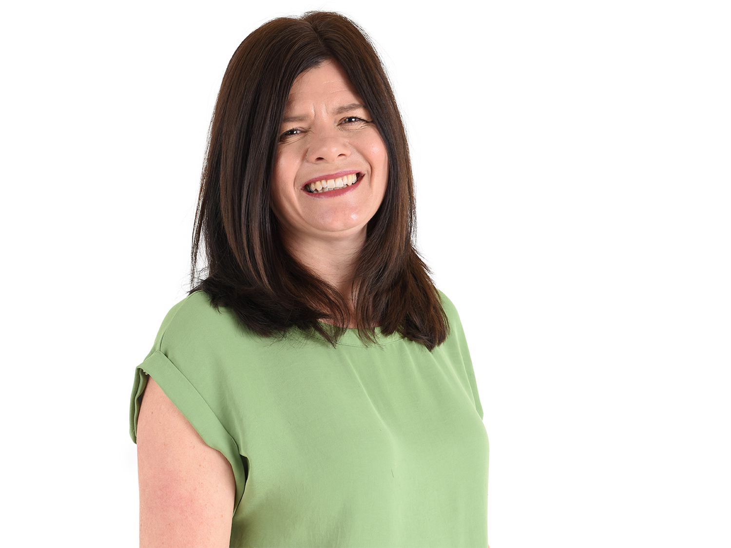 Person wearing a light green short-sleeved top, standing against a plain white background. The individual has shoulder-length dark brown hair styled straight, and the pose is slightly angled to the side.