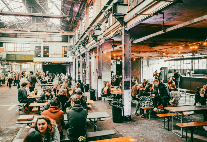 Rows of tables with benches, with people dining, at The Steamworks.