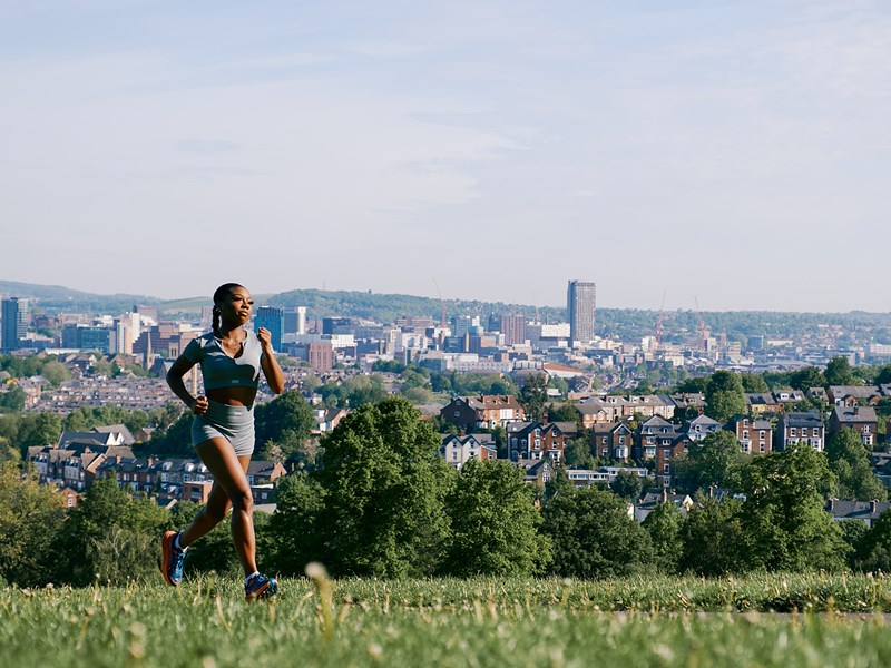 Runner in Meersbrook Park with cityscape view in the background