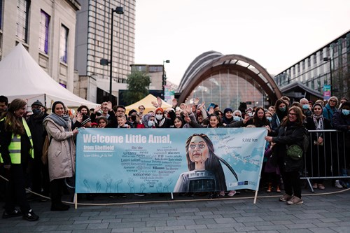 A crowd of people in Tudor Square, in Sheffield City centre, waiting for the arrival of Little Amal.