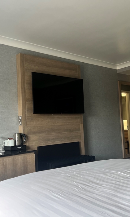 Bedroom with a double bed, wall-mounted TV, and a desk area.