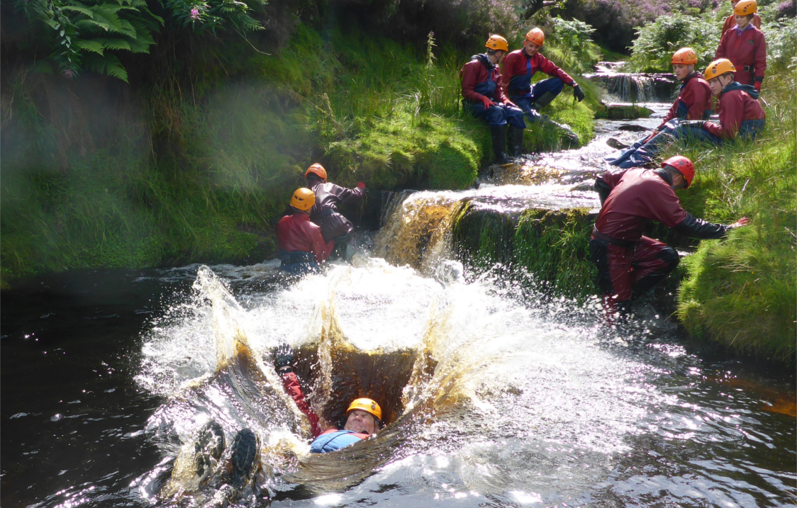 People training in a river, all of whom are wearing safety gear.