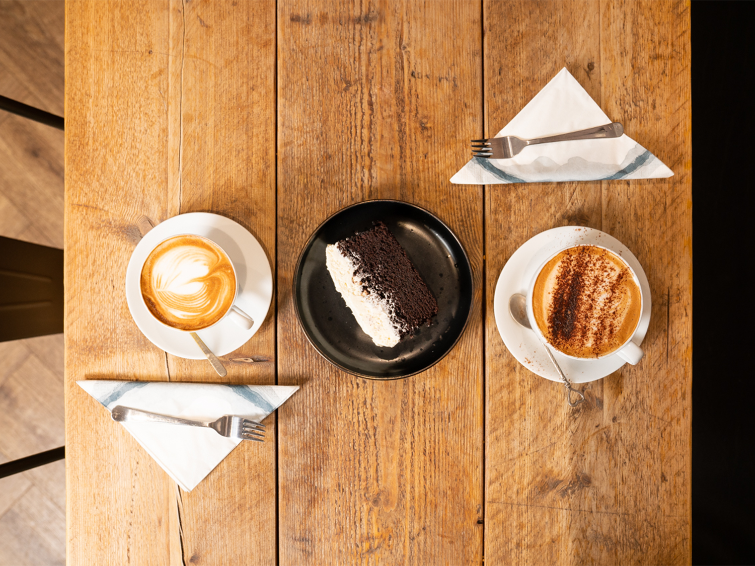 Two coffees on a rustic wooden table.