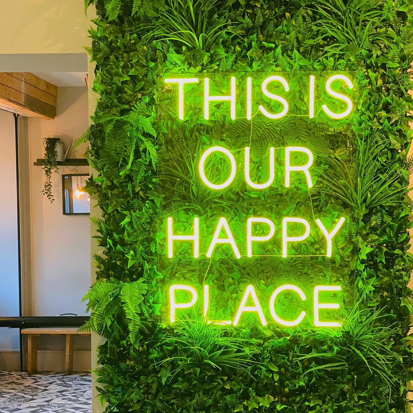 A green neon sign that reads 'This is our happy place' on the wall at S17 Coffee Shop & Bistro.