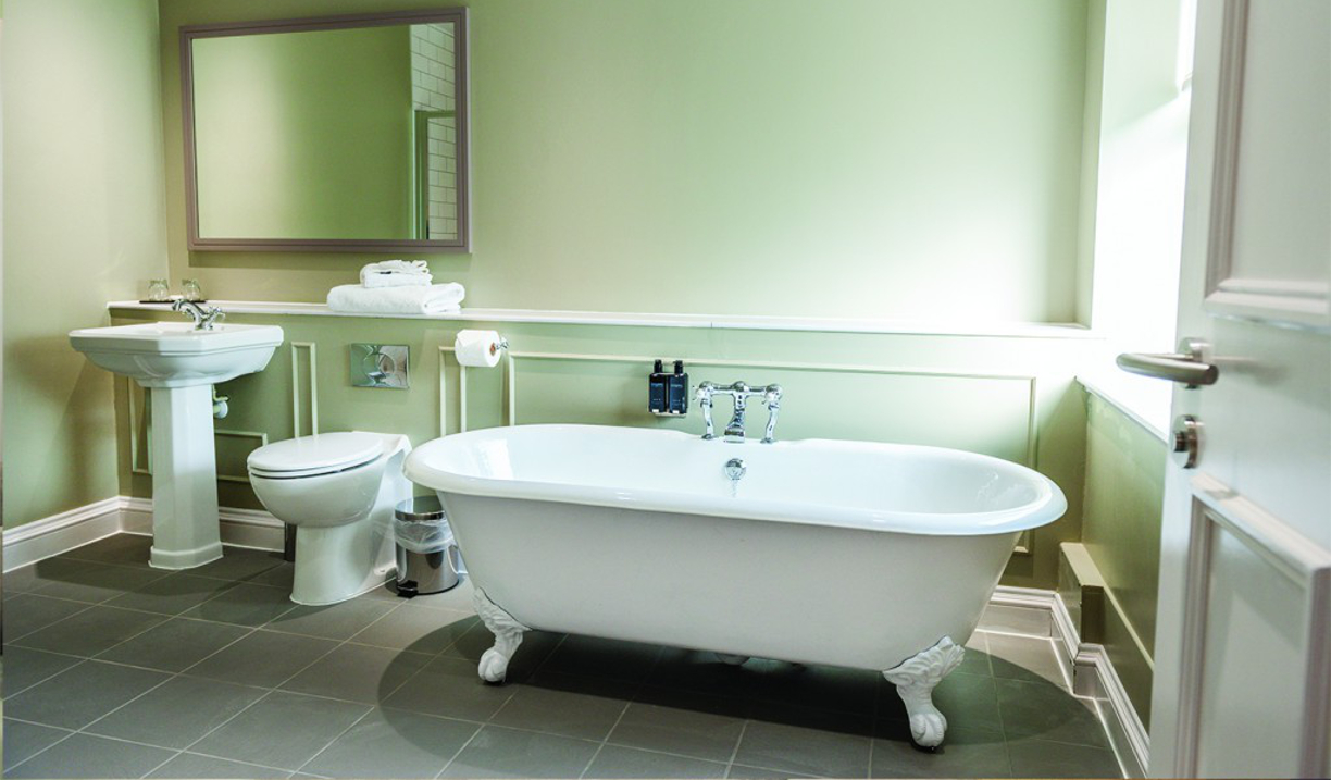Classic white roll-top bath with chrome fittings in a stylish hotel bathroom.