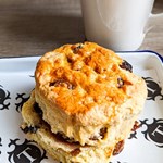 A scone on a plate with a mug of tea.