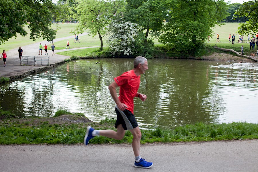 A man running on a path that goes around one of the ponds at Graves Park.