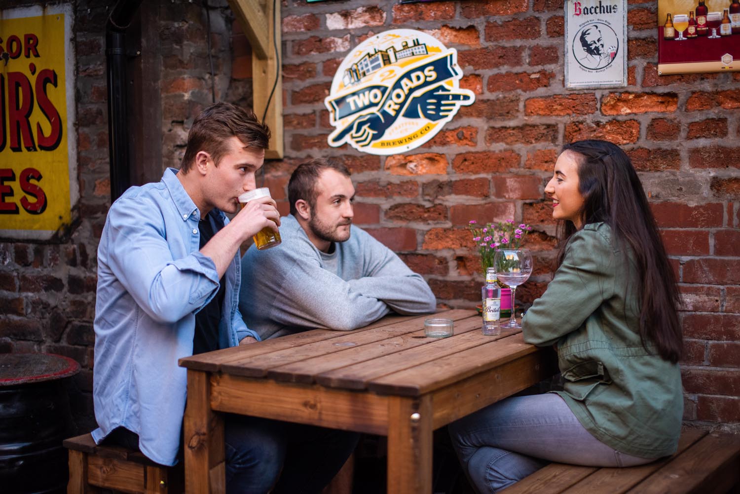 People sat round a rustic table having a pint.