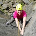 A woman climbing a rock face with a big smile on her face.
