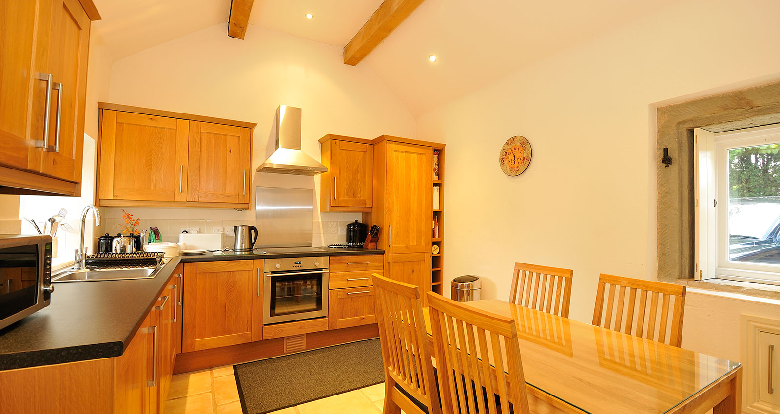 Bright country kitchen with wooden cabinets, countertops, and dining area.