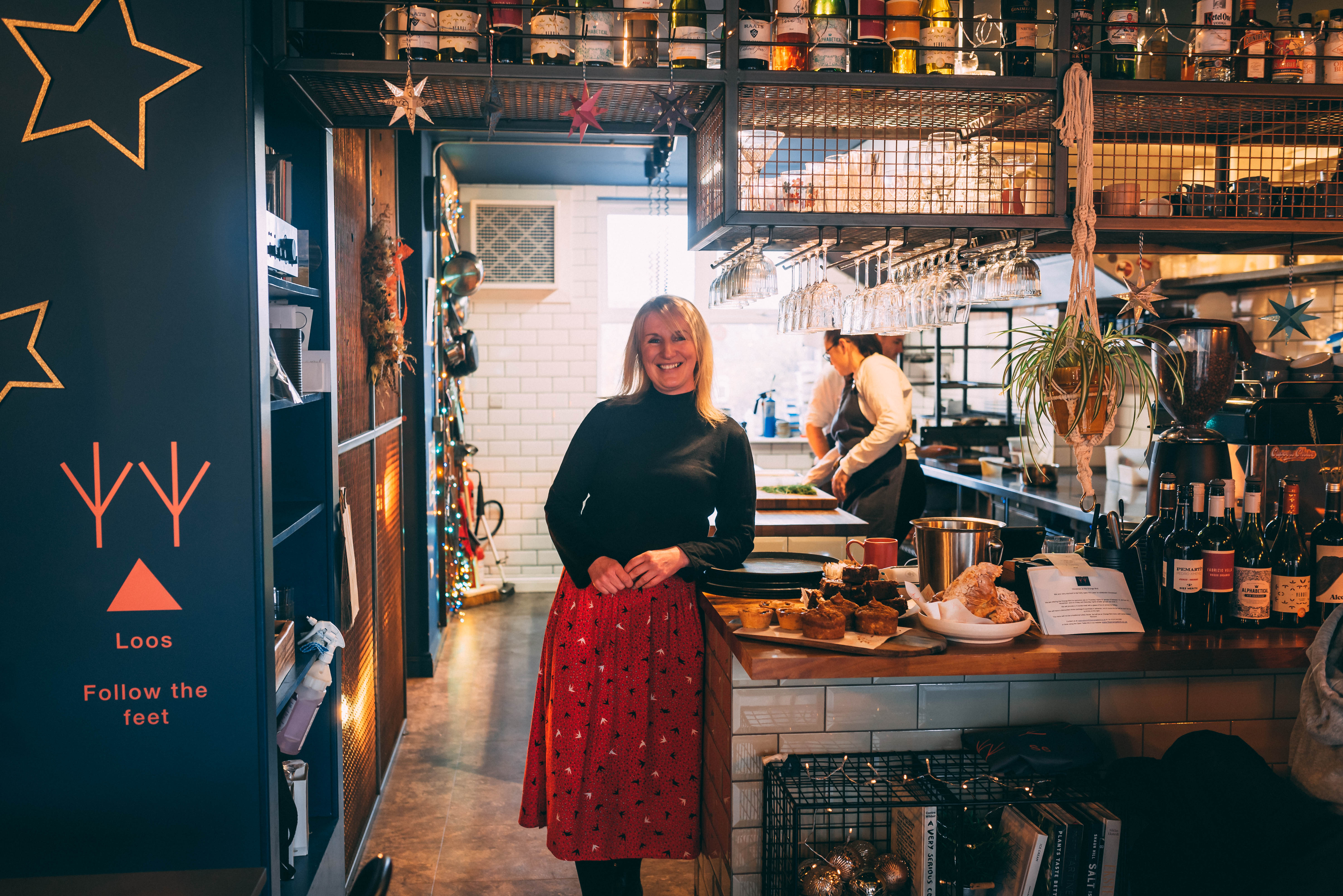 A woman stands smiling in a restaurant kitchen.