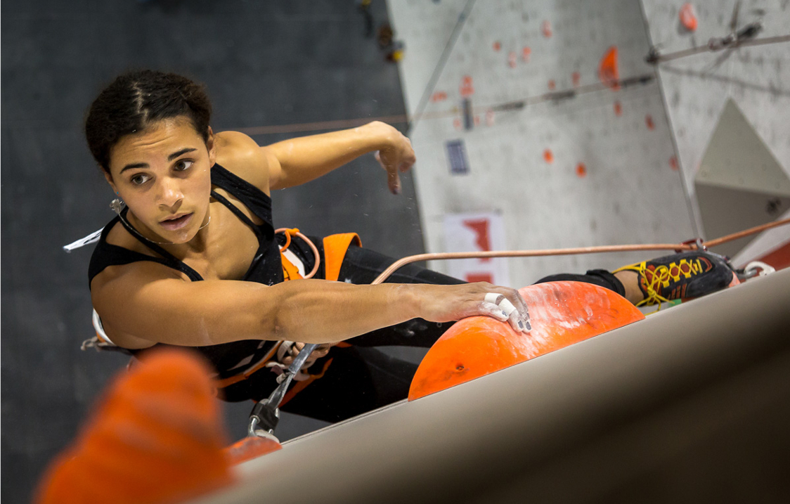 A woman climbing on an indoor climbing wall.