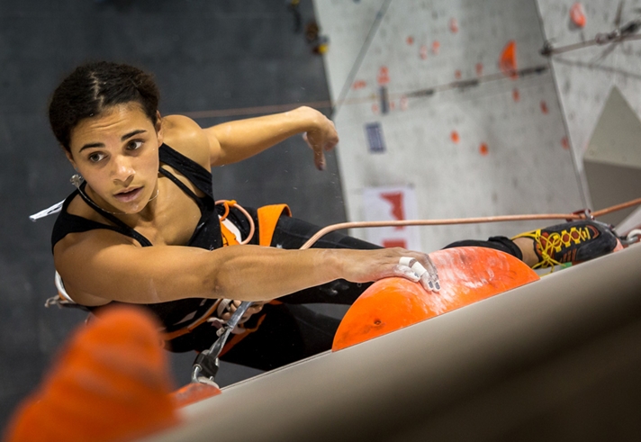 A woman climbing on an indoor climbing wall.