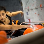 A woman climbing on an indoor climbing wall.