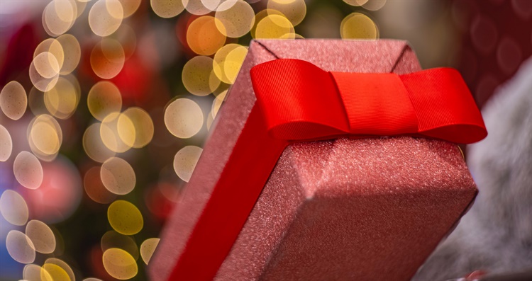 A stock image of a present wrapped in sparkly red paper with a red ribbon.