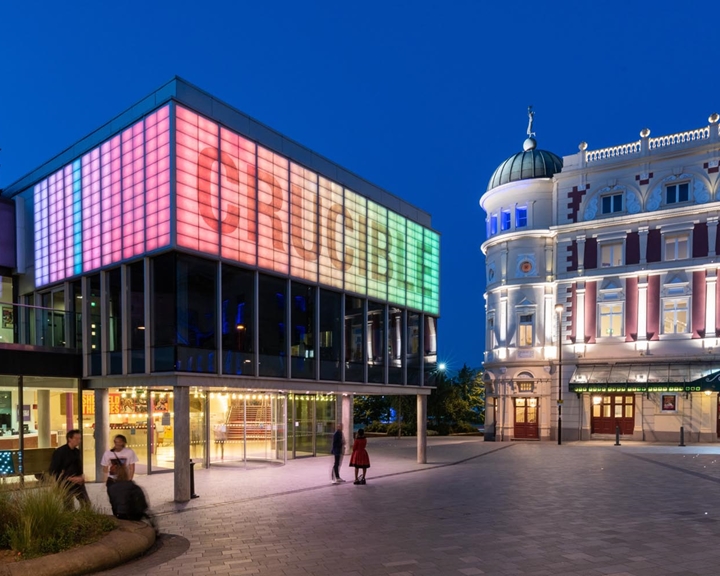 The Crucible and Lyceum Theatres, in Tudor Square in Sheffield, at dusk. Both buildings are well lit and look cheerful and inviting.
