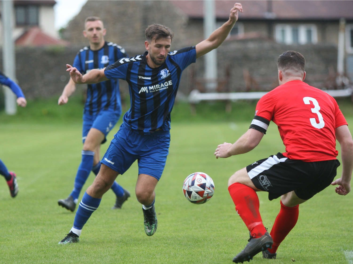 Men playing football in front of a crowd.