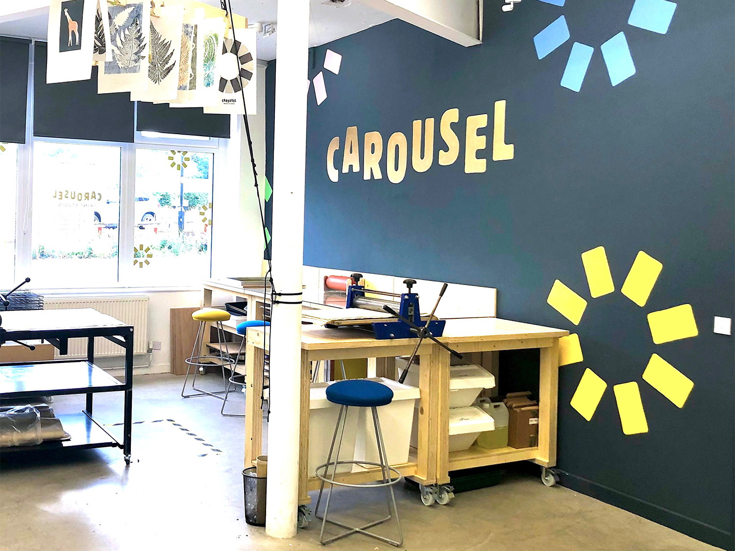 Inside the Carousel Print Studio with all the print equipment and prints hanging from the ceiling to dry.