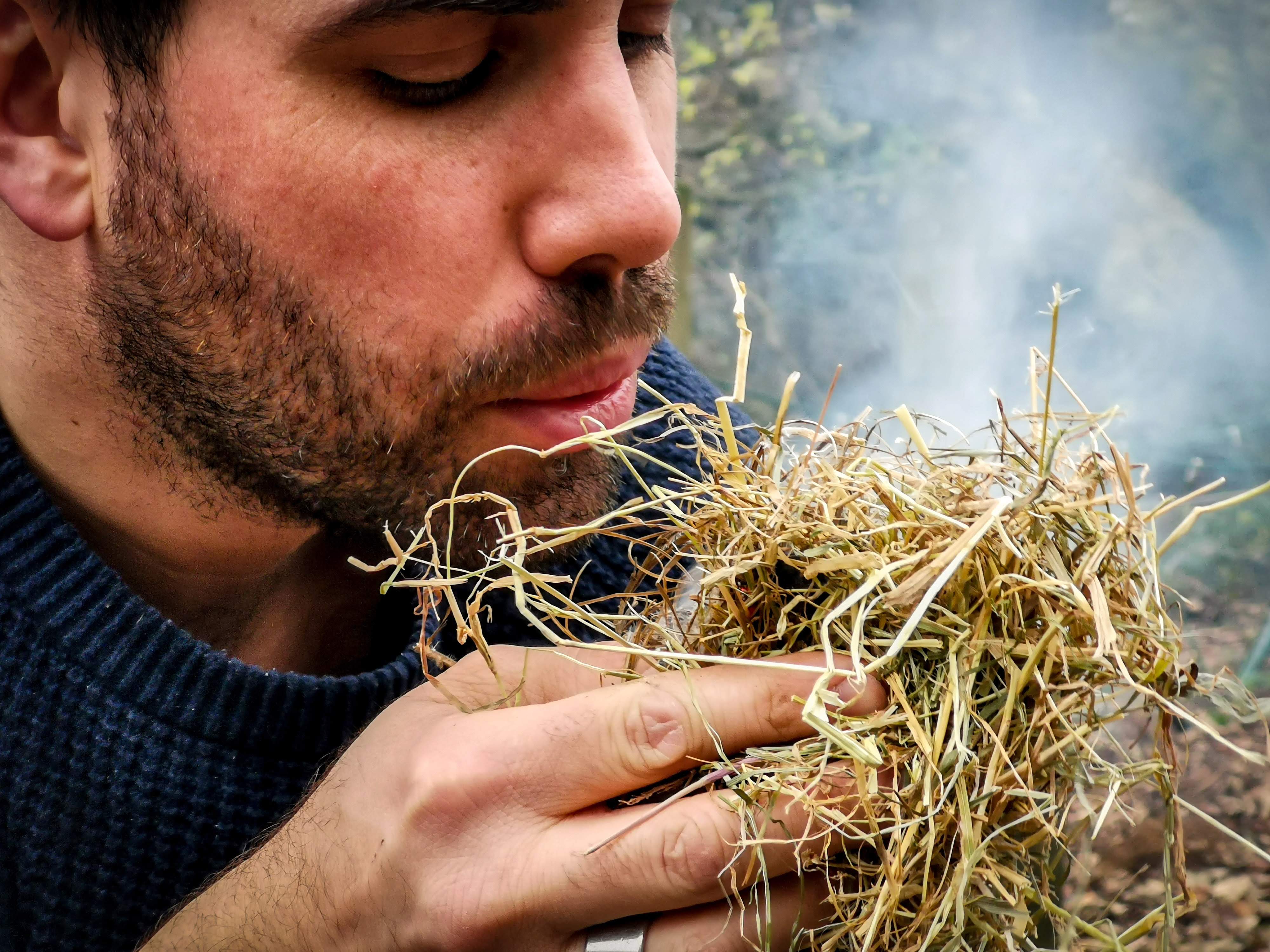 A man is using some tinder to start a campfire at TRIBE Bushcraft Centre