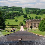 A water feature running down a hill with Chatsworth House in the distance.