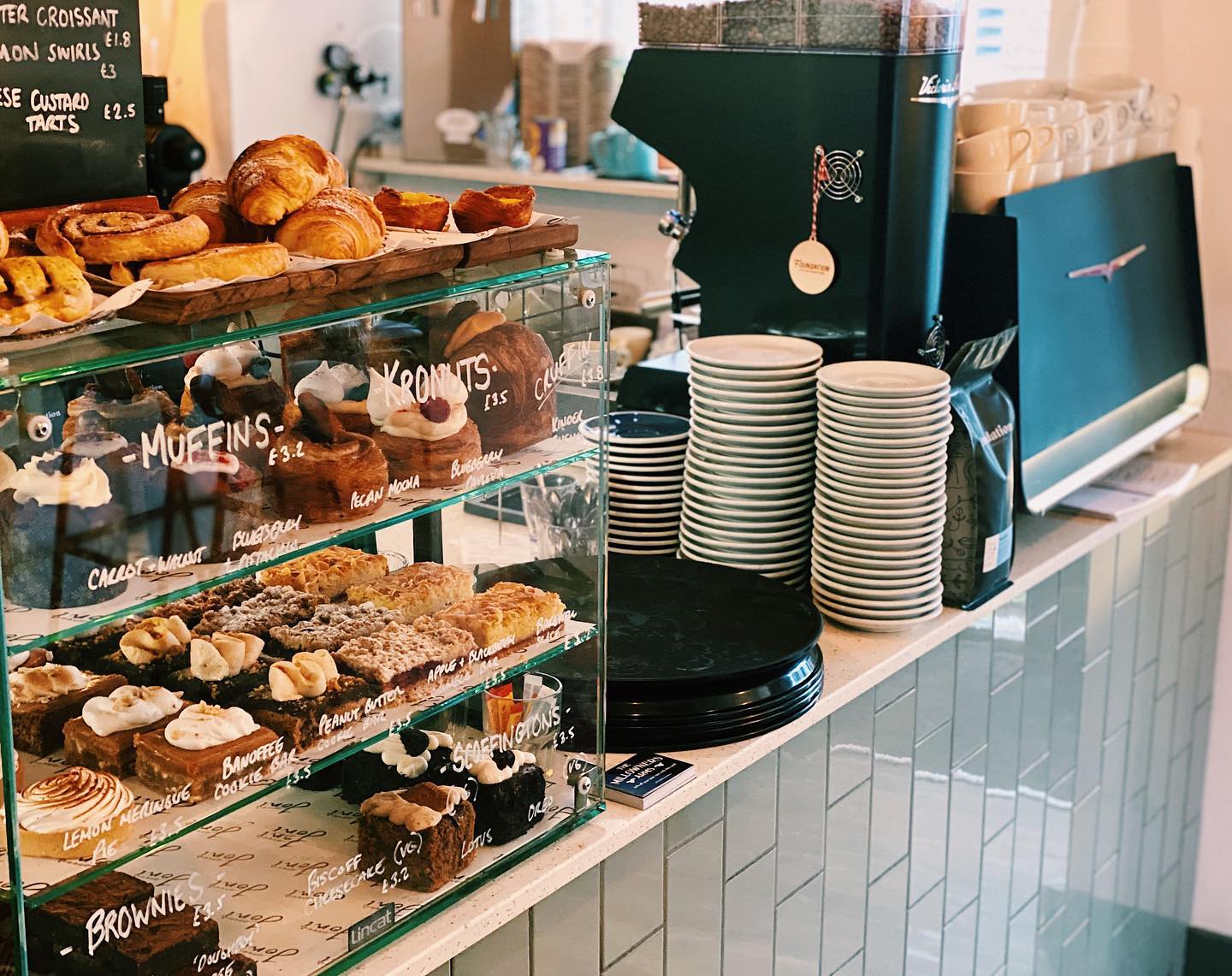 A counter with a coffee machine and a glass case full of pastries.
