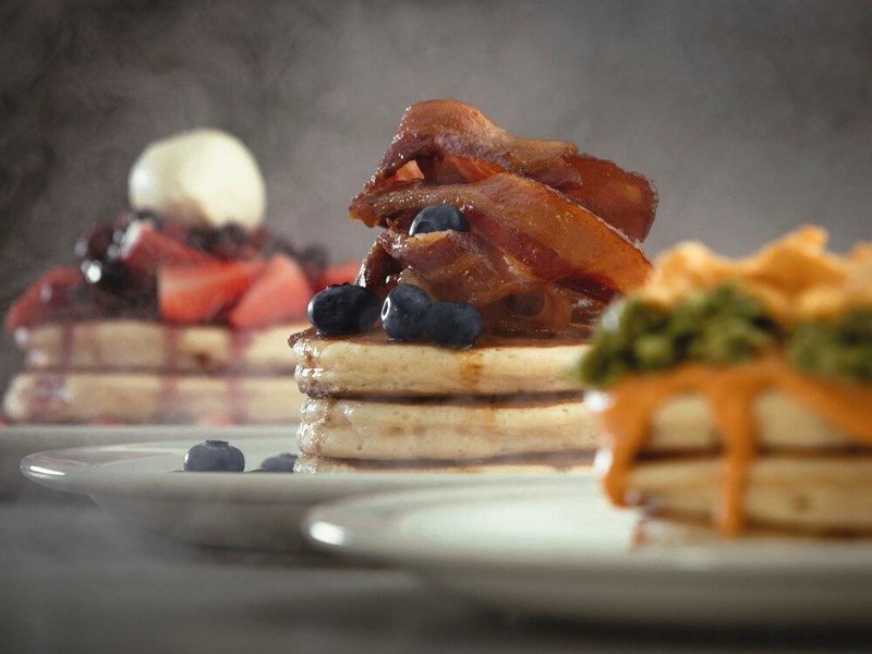 Three plates filled with stacks of pancakes.