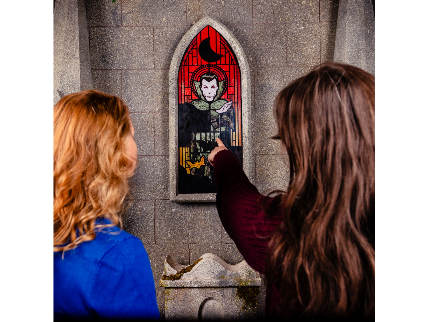 The King of Vampires in Dracula escape room at Escape Hunt Sheffield. Two women are pointing at a stained glass window that depicts a vampire.