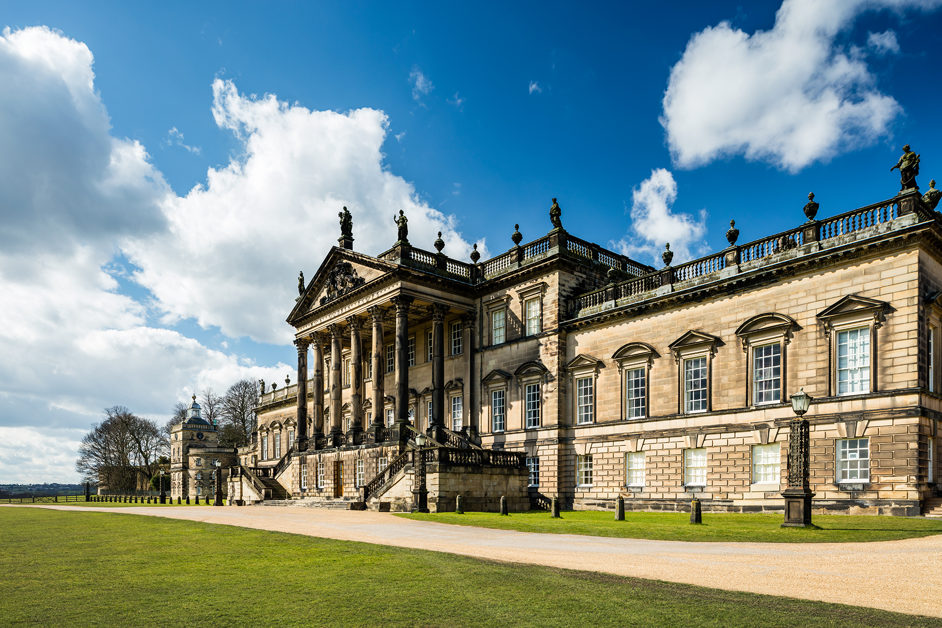 Side angle of the Wentworth Woodhouse viewed from the gardens, showing the imposing architecture against blue skies