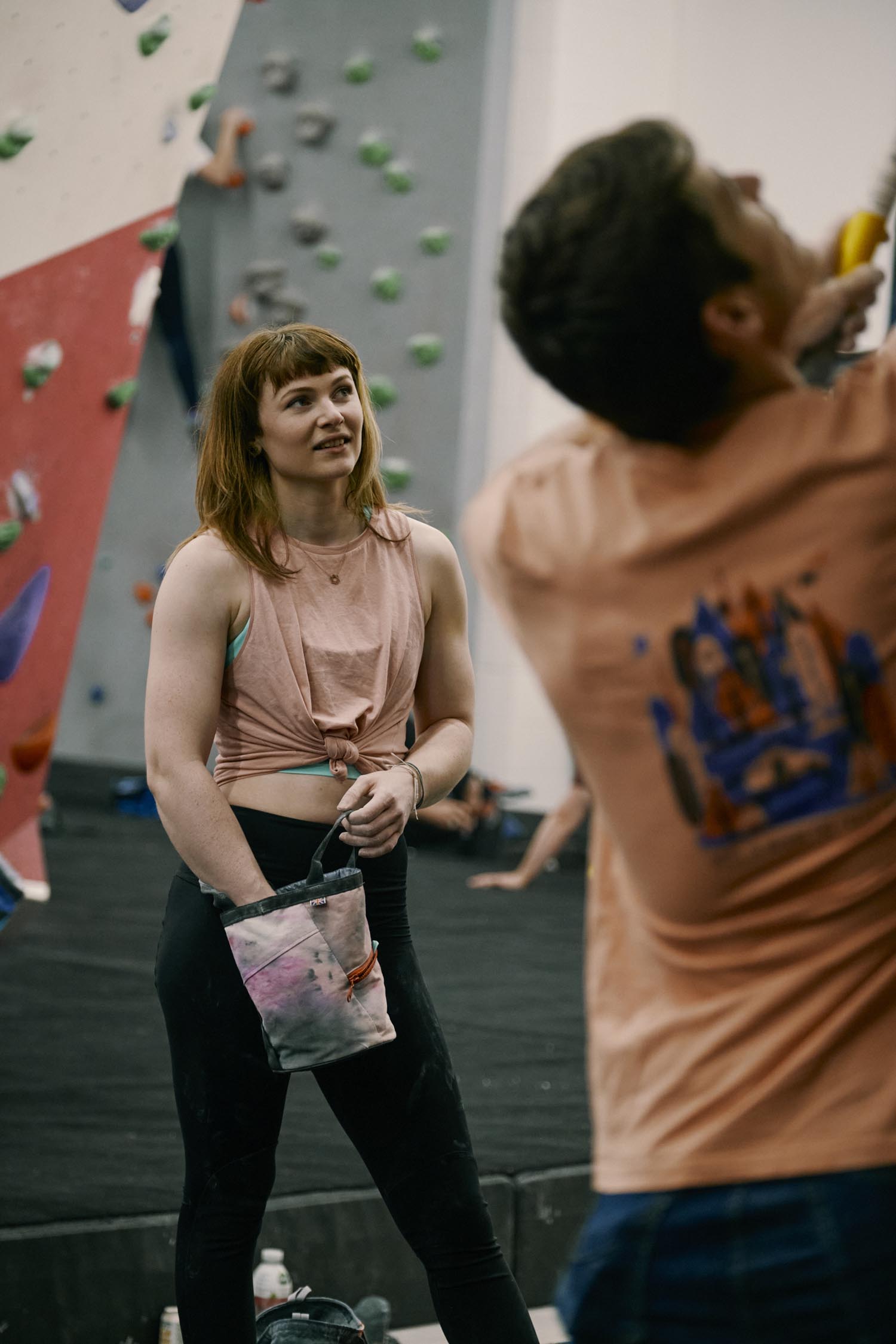 Two people getting ready to climb an indoor climbing wall.