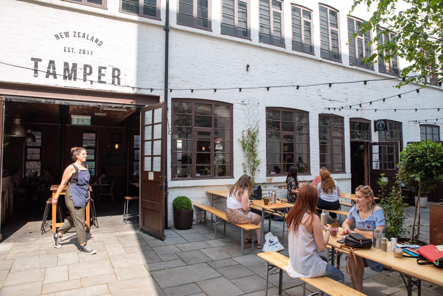 The courtyard at Tamper Coffee, with customers sat at tables.