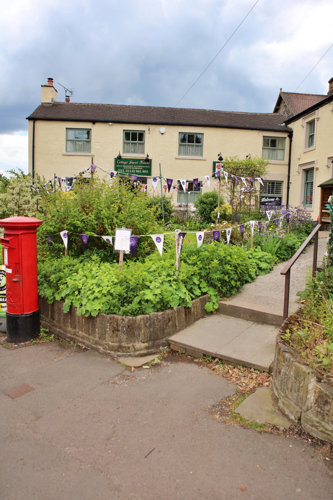 Wortley Cottage Guest House with stone walls, pitched roof, and garden area in front.