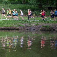 Group of runners participating in a park run alongside a lake.