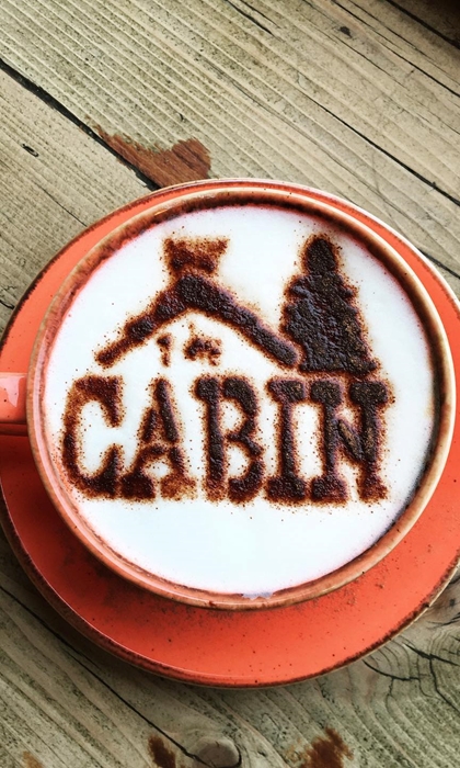 A cappuccino with The Cabin logo dusted onto the froth in chocolate powder.