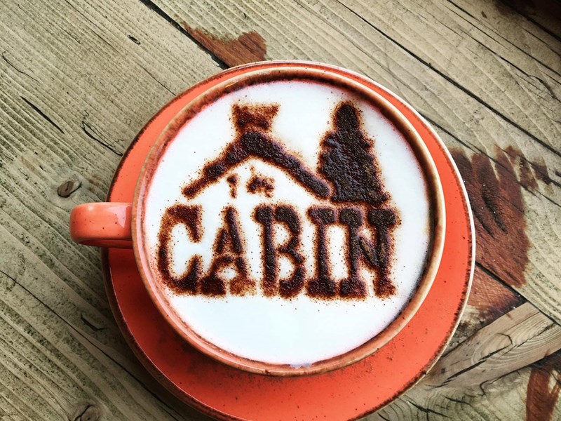 A cappuccino with The Cabin logo dusted onto the froth in chocolate powder.