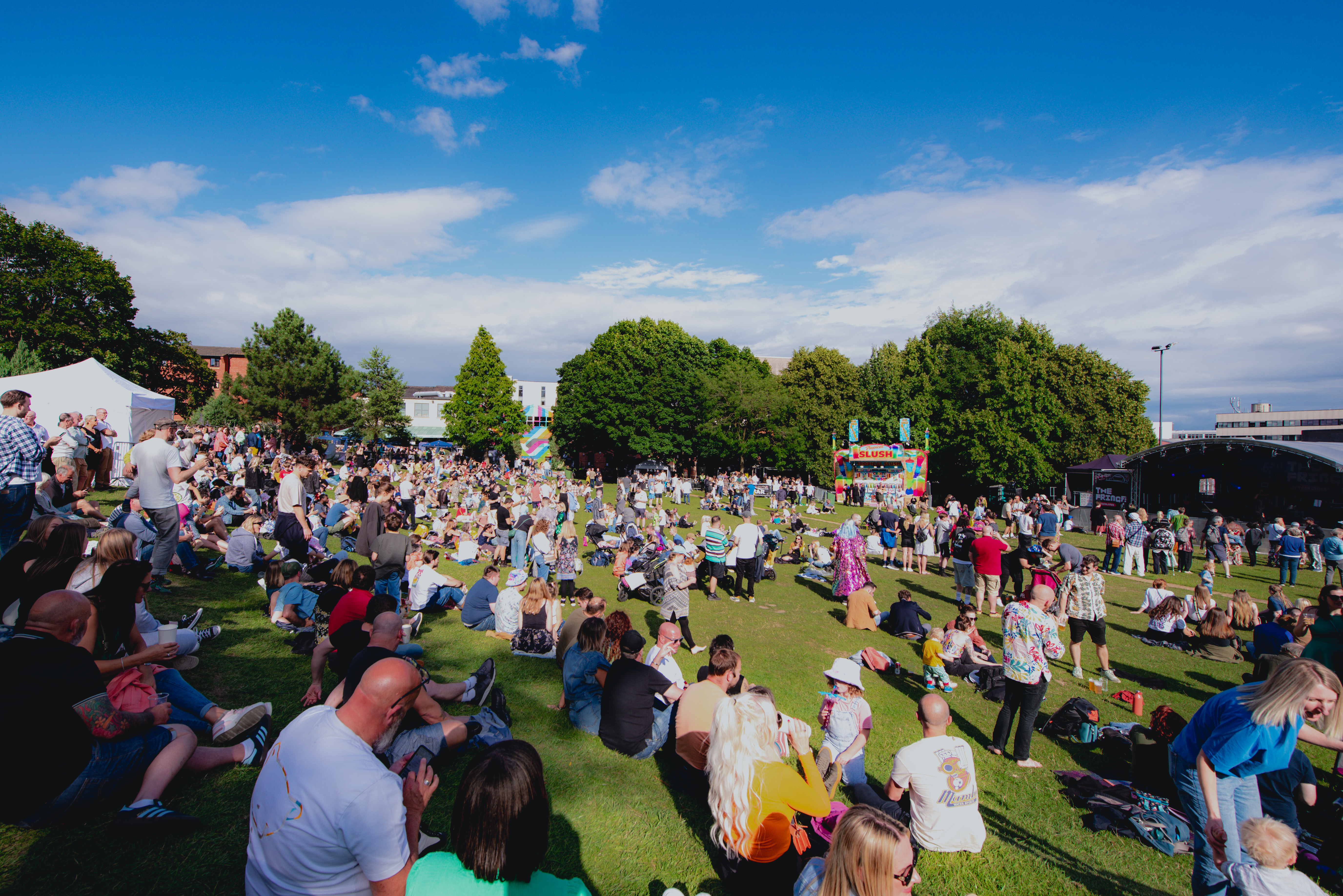 Blue skies over Devonshire Green as groups of people sit in the sunshine watching performances on the Fringe main stage 