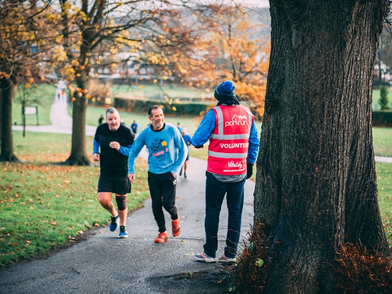 Two runners and a marshal at ParkRun in Hillsborough Park.