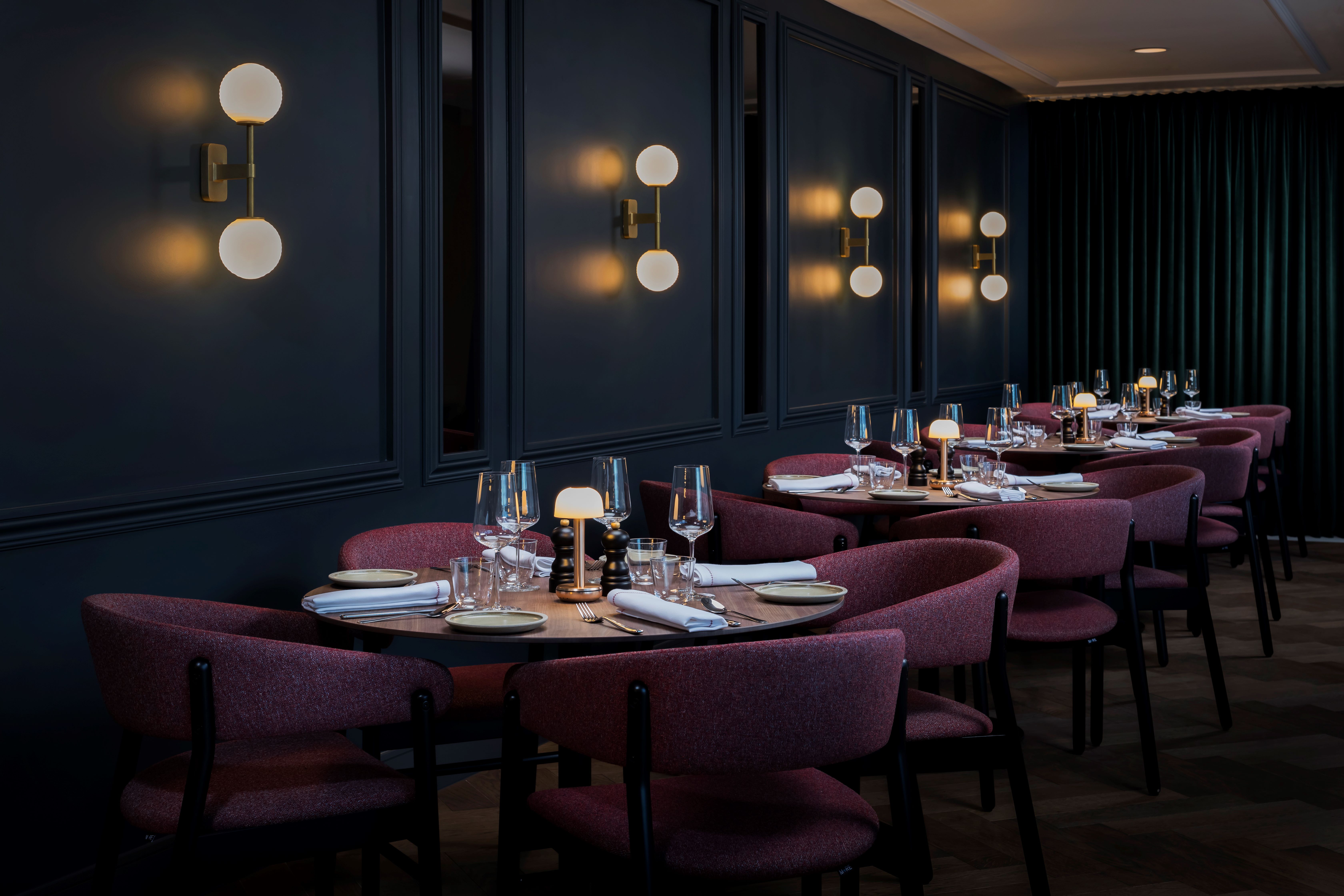 Mood-lit area of the restaurant with round tables set in a row.
