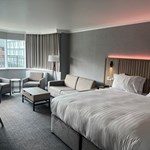 Modern double bedroom with seating area and ambient mood lighting.