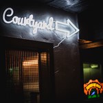 A white neon sign that reads 'Courtyard' on the wall at Monk Bar.