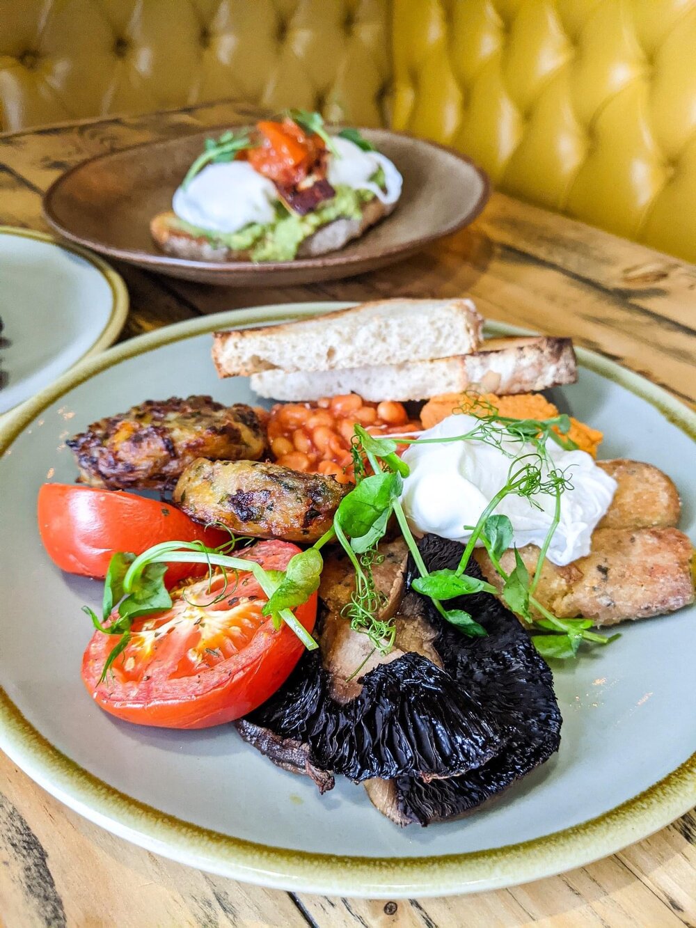 Three plates of food on a wood table in a booth.