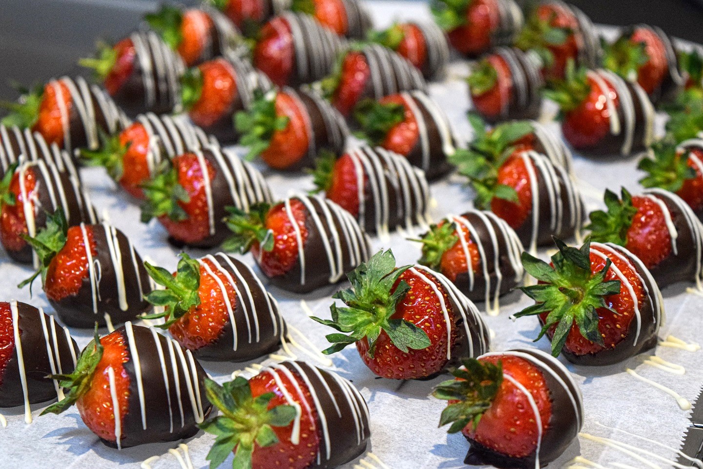 A tray of strawberries that have been drizzled in chocolate.