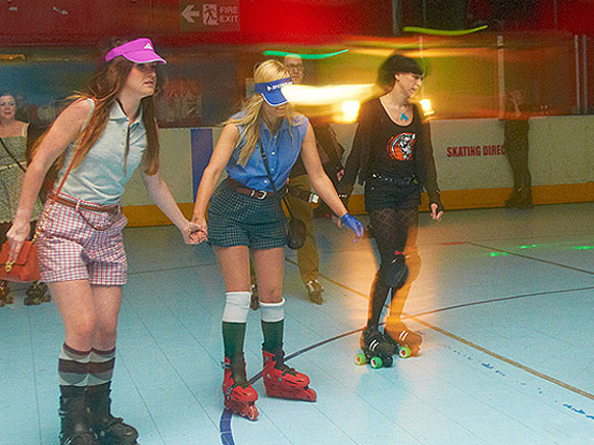 Three people roller skating in a rink. 