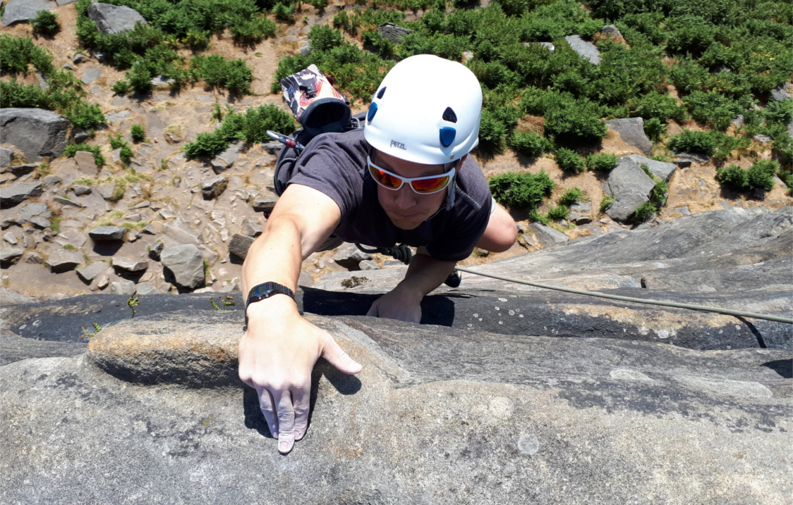 A person climbing up a rock face in the countryside.