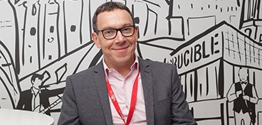 Chris Blundell sat in front of mural of Sheffield.