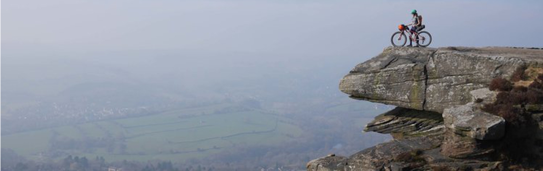 A person, on a mountain bike, on top of a rocky outcrop.