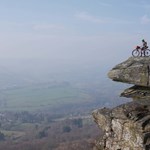 A person, on a mountain bike, on top of a rocky outcrop.