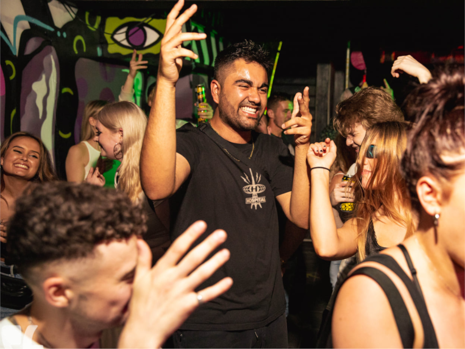 A crowded night club full of people dancing. Everyone is smiling and having fun.