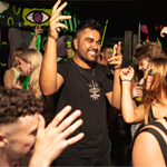 A crowded night club full of people dancing. Everyone is smiling and having fun.